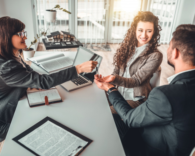 couple assis autour d'une table, la femme tient des clefs de maison et l'homme une maison dans sa main Yvelines 78